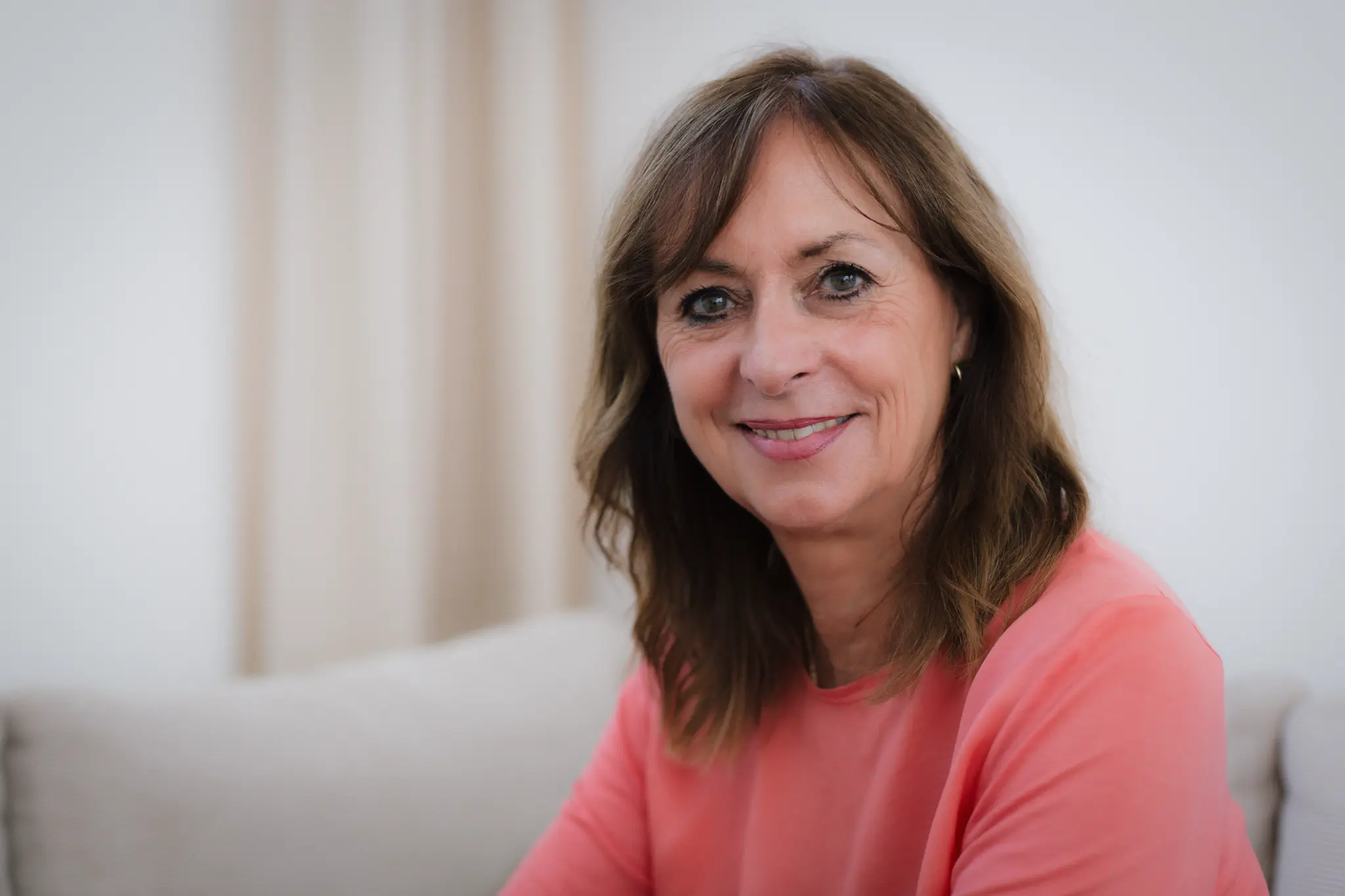 Birgit Bilger lächelt in einem korallfarbenen Oberteil